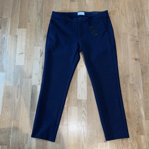 Nya kritstrecksrandiga byxor, Only & Sons - Säljer ett par helt nya mörkblå kritstrecksrandiga kostymbyxor från Only & Sons. Prislappen är kvar och nypris är 400kr. Byxorna har normal passform, knäppning med knapp och dragkedja samt två bakfickor med knapp. Perfekta för en trendig look. Strl 33/34 men passar 33/32! 