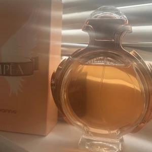 Olympea Eau de Parfum från Paco Rabanne - Olympea Eau de Parfum från Paco Rabanne i en elegant, rund glasflaska. Använt nån gång men har andra perfymer som passar mig bättre därför säljer jag den💖 ”Olympéa är en doft som balanserar fräsch citrus och blommiga noter med en saltig, krämig vanilj och varm träighet. Många beskriver den som feminin, kraftfull, elegant och sexig – perfekt för både dagtid och kväll”