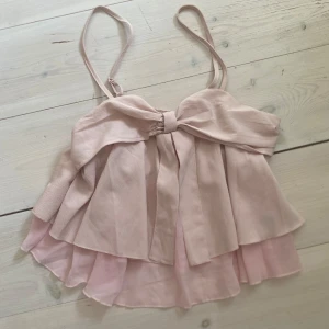 Ljusrosa volangtopp med rosett - Supersöt ljusrosa linnetopp från SHEIN med volanger och stor rosett framtill. Toppen har smala axelband och dubbla lager tyg som ger en flowy känsla. Perfekt för dig som gillar romantisk och feminin stil!