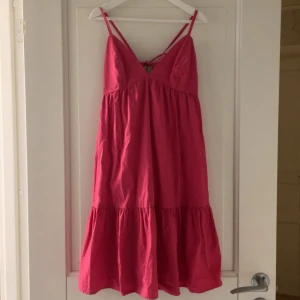 Rosa sommarklänning med knyt i ryggen - Säljer en söt rosa klänning perfekt inför sommaren❣️Klänningen har volang nertill, smala axelband och knytning i ryggen med rosett för en justerbar passform. Perfekt för varma dagar och har en luftig, avslappnad stil.