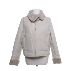 Ljusbeige jacka med fuskpälsdetaljer - Säljer en ljusbeige jacka med mjuk fuskpäls vid krage och ärmslut. Jackan har dragkedja framtill och två fickor. Perfekt för kyligare dagar och ger en stilren look.