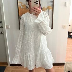 Vit blommig klänning med volang - Säljer en söt klänning från NAKD, aldrig använd. 