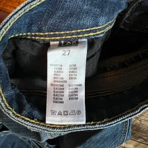 Blå jeans från Lee med gul söm - Säljer ett par klassiska blå jeans från Lee med snygga gula sömmar och detaljer på bakfickan. Jeansen har normal passform och är tillverkade i bomull med lite stretch för extra komfort. Perfekta till vardags och enkla att matcha.