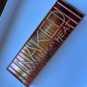 Urban Decay Naked Heat ögonskuggspalett - Urban Decay Naked Heat ögonskuggspalett med 12 nyanser i varma toner som beige, koppar, brons, rödbrun och mörklila. Paletten har en spegel i locket och är perfekt för att skapa både naturliga och dramatiska ögonlooker. Sparsamt använd så är i fint skick! Tyvärr följer inte borsten med.