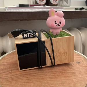 BT21 digital klocka  - Digital klocka i trälook med en söt rosa BT21-figur på konstgräs. Klockan har USB-anslutning och display på framsidan. Perfekt som accessoar till skrivbordet eller nattduksbordet. Nypris 1200kr