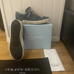 Mörk blå sneakers från Philippe Model - Snygga blåa sneakers från Philippe Model med vita snören och en vit sula. Skorna har en stilren design och är i toppskick 