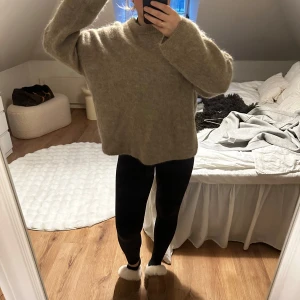 Beige stickad tröja från H&M Edition - Mysig beige stickad tröja från H&M Edition. Perfekt för kyliga dagar med sin mjuka och varma känsla. Tröjan har en klassisk rund hals och långa ärmar, vilket gör den till ett mångsidigt plagg i garderoben. använd 1 gång