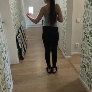 Svarta leggings från Nike - Snygga svarta leggings från Nike med deras klassiska logga på benet. Perfekta för träning eller en avslappnad dag. De har en tight passform och är tillverkade i ett bekvämt syntetmaterial.