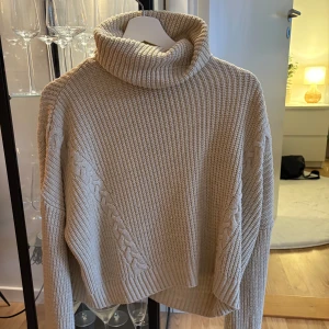Beige stickad polotröja - Säljer en mysig beige stickad polotröja med kabelstickade detaljer.