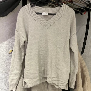 Stickad tröja - Mysig beige stickad tröja från Vila med v-ringad hals och ribbade detaljer vid ärmslut och nederkant. I storlek xs