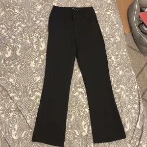 Svarta kostymbyxor från BikBok - Snygga svarta kostymbyxor från BikBok i storlek 34. Byxorna har en klassisk design med boot cut och är perfekta för en stilren look. De är tillverkade i ett bekvämt material som ger en elegant känsla.