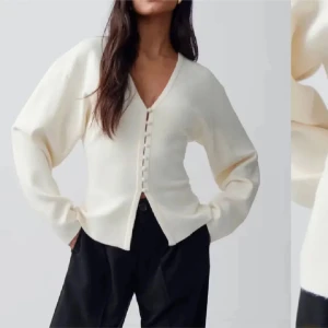 Vit kofta med knappar - Säljer en stilren vit kofta med v-ringning och knappar framtill. Perfekt för en elegant och avslappnad look. Koftan har långa ärmar och en mjuk passform.