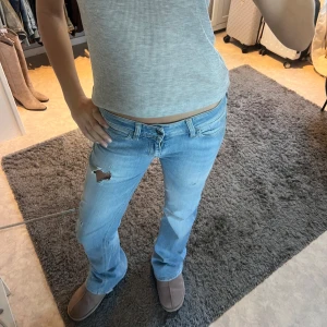 Ljusblå jeans med slitning - Lågmidjade jeans bootcut , mår midja rakt över 38cm , innerbenslängd 80cm , jag är 168cm