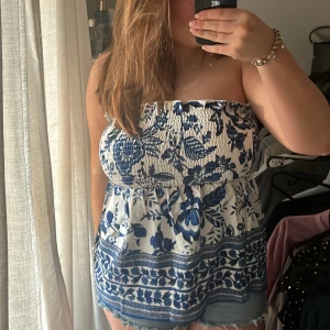 Blåvit blommig tubtopp från Shein - Säljer en söt blåvit tubtopp från Shein med blommigt mönster. Skit fin till sommaren!!! Den är ärmlös och har en elastisk överkant för bra passform. ALDRIG ANDVÄND 