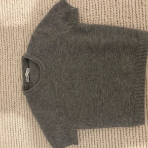 Grå kortärmad tröja från Zara - Säljer en stilren grå tröja från Zara. Den är kortärmad och har en rund halsringning med ribbade kanter. Perfekt för en avslappnad look. Är i super bra skick! Hör av er vid några frågor