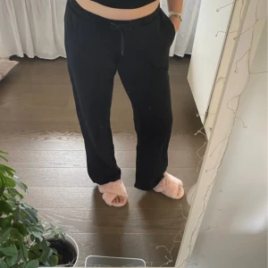 Svarta raka mjukisbyxor med knytning i midjan - Säljer ett par svarta mjukisbyxor med knytning i midjan. Perfekta för en avslappnad dag hemma. Byxorna har en loose passform och är tillverkade i ett mjukt material för extra komfort. De är endast använda 1 gång. Passar en storlek M
