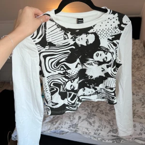 Vit och svart långärmad topp - Säljer en cool vit och svart långärmad topp med ett unikt grafiskt mönster. Toppen har en rund hals och är perfekt för att ge din outfit en edgy touch. Passar bra till jeans eller kjol för en avslappnad look. Liten i storleken - passar bra till S/M. Aldrig använd! Önskar du veta exakta mått? Tveka inte att höra av dig!