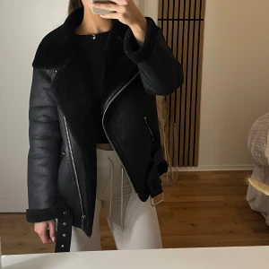 Svart skinnjacka från Zara - Snygg svart pilot skinnjacka från Zara med mjuk insida, dragkedja och bälte i midjan. 