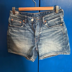 Blå jeansshorts från Weekday - Snygga blå jeansshorts från Weekday med klassisk femficksdesign och knappgylf. De har en normal passform och är tillverkade i slitstarkt denim. Mycket fina, har växt ur dem bara! Perfekt nu inför sommaren🩷
