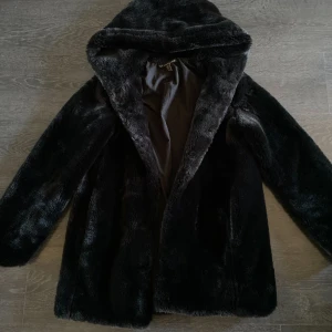 Svart pälsjacka med huva - Säljer en mysig svart jacka i pälsimitation med huva. Storlek S.