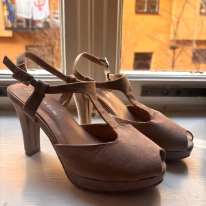 Beiga klackskor  - Snygga beige klackskor från DS med öppen tå och justerbara remmar i storlek 36. Skorna har en elegant design med 8-9 cm klack och är perfekta för att lyfta din stil. Nästan aldrig använda mycket bra skick. Säljer för att de är för små. 