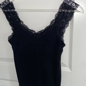 Svart linne med spetsdetaljer - Snyggt svart linne med spetsdetaljer från PIECES i storlek XS😻Använt 1-2 gånger och säljer då jag inte använt de på länge💕