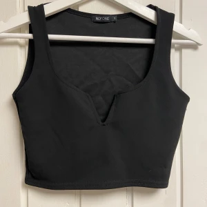 Svart croppad linnetopp från Nelly - Snygg svart croppad linnetopp från Nelly, toppen har en stilren design med en djup v-ringning och breda axelband.