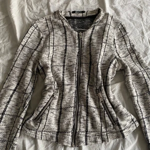 Vintage Rutig jacka med dragkedja - Snygg rutig jacka i svart och beige med dragkedja framtill. Jackan har långa ärmar och två praktiska fickor med dragkedjor. Perfekt för en stilren look. sparsamt använd, tröjan är från Gina Tricot och passa folk som bär S - M 