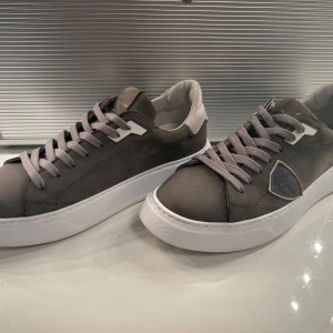 Grå sneakers med vita sulor - Snygga grå sneakers med vita sulor och grå snörning. Skorna har en stilren design med vita detaljer och en diskret blå linje vid hälen. Perfekta för en avslappnad stil. Kan räckna på två händer hur många gånger dessa är använda. Några enstaka små stänk annars helt felfria skor, de defekter som finns syns på bilderna. Köpt för precis ett år sen för 3500kr. 