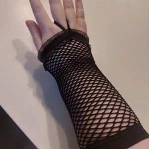 Svarta nätmönstrade handskar - Snygga svarta nätmönstrade handskar med elastisk rem runt fingret. De är fingerlösa och har en dekorativ kant upptill. De är elastiska och kan passa de flesta! Skriv om ni har någon fundering!✨️