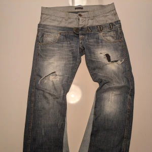 Blå jeans från Angel Devil Jeans - Snygga blå jeans med slitna detaljer och broderad text på linningen. Custom flared. Mått och fler bilder i dms.