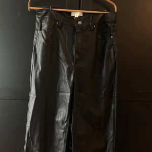 Svarta byxor i fakeläder - SÄLJER Utsvängda byxor från H&M i fakeläder, använda men i bra skick. 