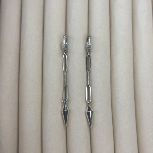 Silverfärgade örhängen med kedjor och spetsig detalj - Säljer ett par långa, silverfärgade örhängen med kedjelänkar och en spetsig, konformad detalj längst ner. Örhängena har glittriga detaljer vid fästet och en modern, edgy design. Perfekta för dig som vill sticka ut!