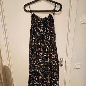 Svart/beige mönstrad långklänning - Säljer en svart klänning med beige prickigt mönster och smala axelband från Only. Klänningen har en avslappnad passform och är perfekt för varma dagar. Lätt och luftig modell som ger en snygg siluett. Längre än vad bilden visar! Använd ett fåtal gånger👗