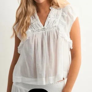 Vit blus med volangdetaljer - Säljer en luftig vit blus med v-ringning och volangdetaljer vid axlarna. Blusen har spetsinslag och är ärmlös, perfekt för varma dagar. Tillverkad i bomull för en skön och sval känsla.