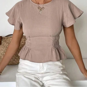 Beige blus med volangärmar - Säljer en beige blus med rund halsringning och korta volangärmar. Toppen har markerad midja med rynkade detaljer. Perfekt för en stilren och trendig look.💗💗
