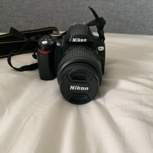 Nikon D60 systemkamera med objektiv - Säljer en svart Nikon D60 systemkamera med originalobjektiv 18-55mm. Kameran har tydlig display, flera manuella och automatiska inställningar samt rem för enkel hantering. Perfekt för dig som vill börja fotografera med systemkamera.