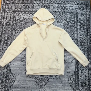 Beige hoodie med tryck AMEN - Säljer en beige hoodie i storlek L. På ryggen finns blå text med ordet 'AMEN' i grafisk stil. Perfekt för en avslappnad stil.