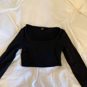 Svart croppad topp från SHEIN - Säljer en svart croppad långärmad topp från SHEIN med fyrkantig ringning. Perfekt att styla med höga jeans eller kjol. Enkel och stilren design som passar till många olika looks. I storlek petite xs
