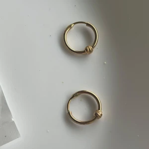 Guld örhängen i 18k - Säljer ett par guld örhängen i 18k  med en vriden detalj på ringen. Perfekta som diskreta vardagsörhängen eller för att kombinera med andra smycken. Klassisk och stilren design.