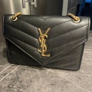 Svart axelväska - Säljer en svart axelväska med kedjerem i guld. Harett fack med dragkedja inuti. Perfekt accessoar för att lyfta din outfit. 