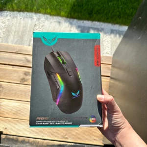 RGB Gaming Mouse - Säljer en svart gamingmus med RGB-belysning och optisk sensor. Musen har 6400 DPI, inbyggd fire-knapp och anti-svettfilter. Utrustad med 1,5 m flätad kabel och passar för Windows-system. Perfekt för gaming med flera programmerbara knappar.