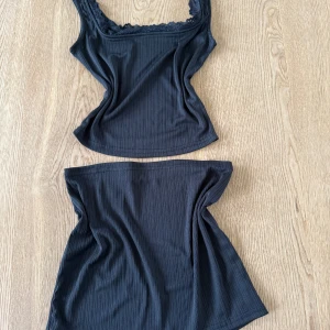 Gulligt sett - Säljer ett set med en svart ribbad linnetopp med spetsdetalj vid urringningen och en matchande svart kjol. Perfekt att styla tillsammans eller var för sig. Perfekt till sommaren!!☀️💖 Helt nya - endast testade
