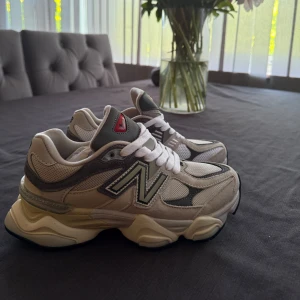 New Balance sneakers i beige och grå - Säljer ett par New Balance sneakers i beige och grå med vita detaljer. Skorna har meshpaneler för extra andningsförmåga, klassisk snörning och en chunky sula med Abzorb-dämpning. Perfekta för en sportig och trendig look.