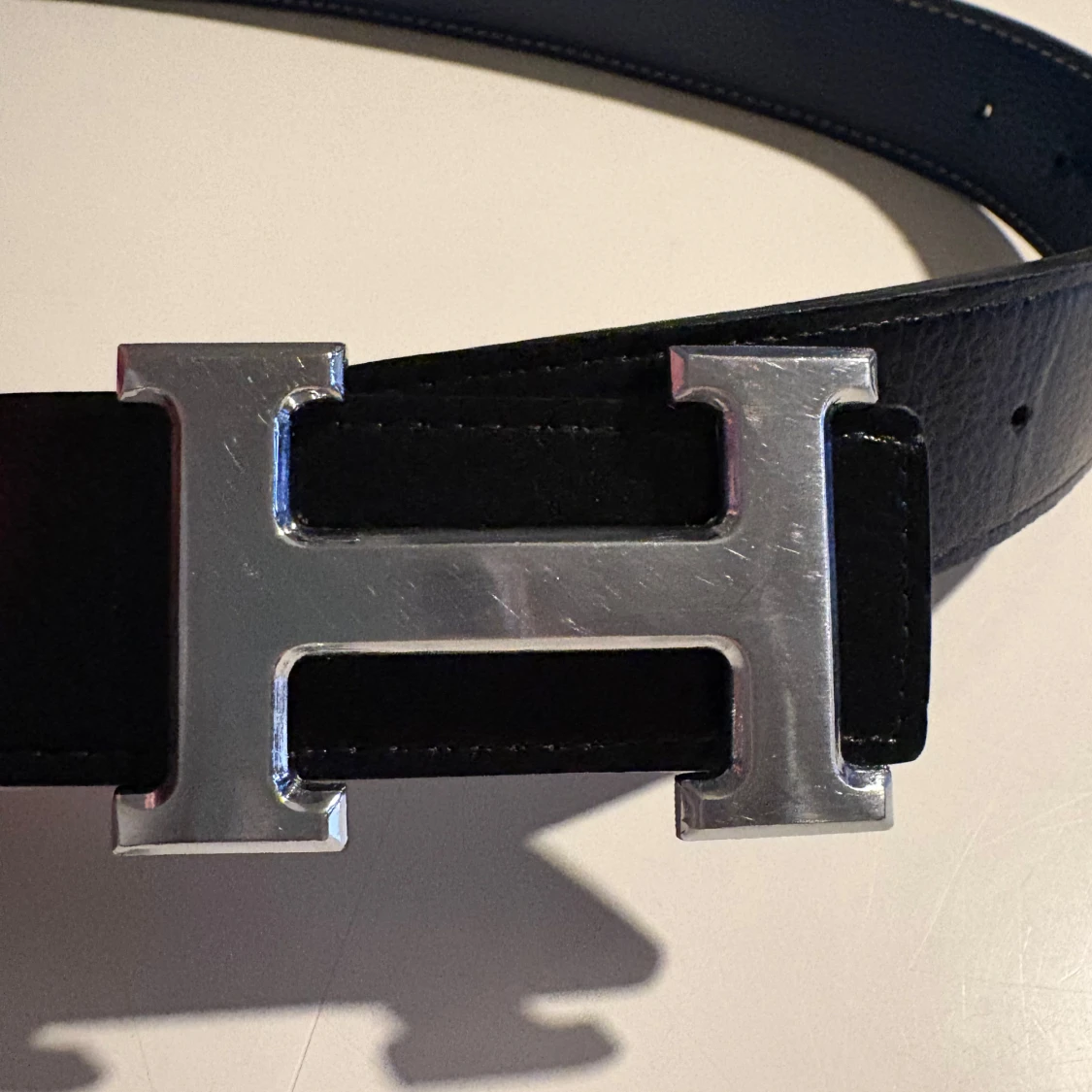 Svart skärp med silverfärgat H-spänne