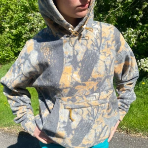 Camo fleece hoodie - Säljer en hoodie från Weekday i grått och orange med camouflagemönster. Tröjan har huva med dragsko och en stor magficka. Jätteskön i fleece!