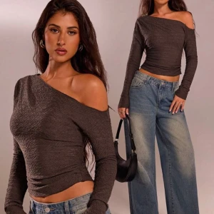 Brun oneshoulder topp - Säljer en brun oneshoulder topp med lång ärm och tight passform. Toppen har en snygg struktur i materialet och är perfekt att styla med jeans eller kjol. Har aldrig använt den för den passar inte mig ( kom privat om ni vill att jag skickat bild på den)