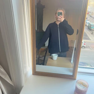 Svart zip-jacka från COS - Säljer en mörkblå bomber jacka från COS. Jackan har silverfärgad dragkedja framtill och ribbad krage. Strl M och oversized! Bra skick!