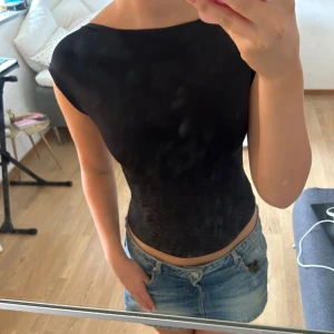 Svart topp med öppen rygg - Säljer en svart, tight topp med korta ärmar och riktigt snyggt öppen rygg. Toppen har en enkel, stilren look och sitter figurnära. Köpte den i en butik i Spanien och har inte lappen kvar så storleken står inte men om jag minns rätt var de xs/s 💕