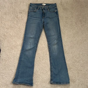 Blå bootcut jeans - Snygga blå jeans från Gina Tricot i storlek 152. Modellen har bootcut-ben och klassisk femficksdesign med coola ficklock bak. Jeansen är i mjukt denimtyg och har en tidlös blå tvätt som passar till allt!